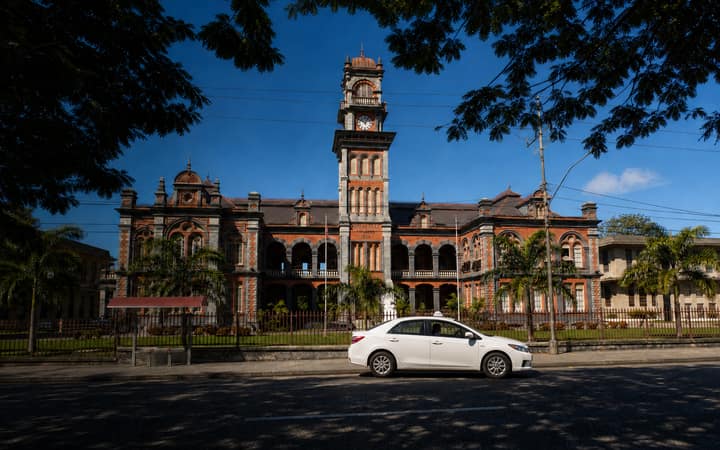 Taxi travelling past Queen's Royal College in Port of Spain